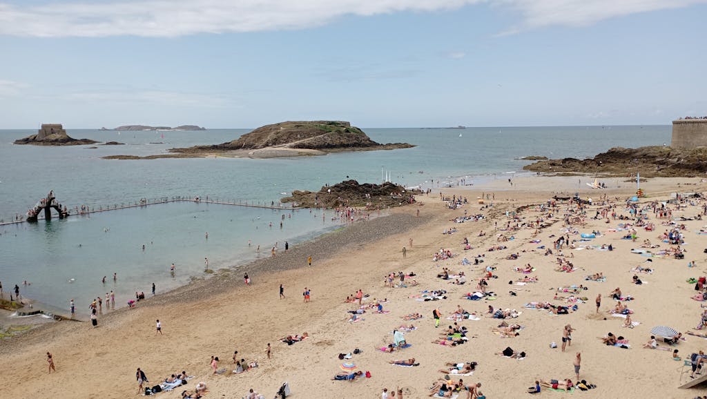 A sunny day at Saint-Malo beach with tourists enjoying the seaside views.